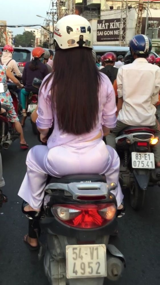 ピンクのアオザイを着てバイクに乗っている女子学生